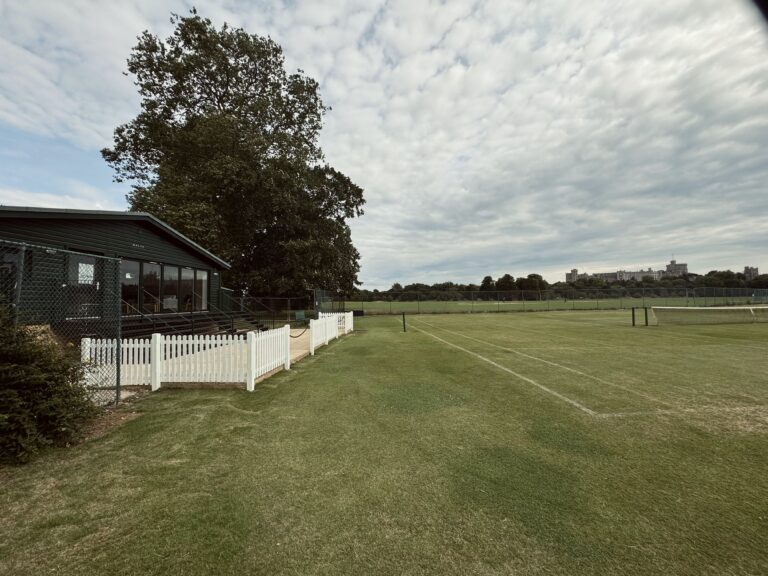 Front view of the green clubhouse with the white little fence.