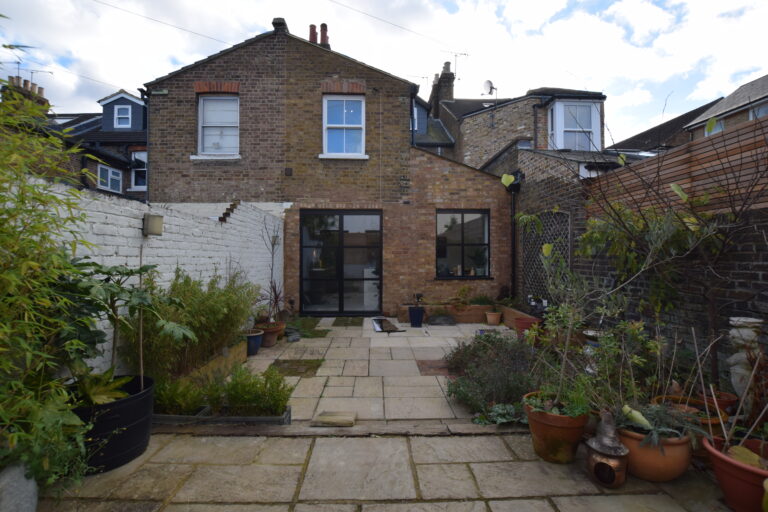 Rear elevation of a victorian property with rear-side extension. Brick walls and dark framed openings